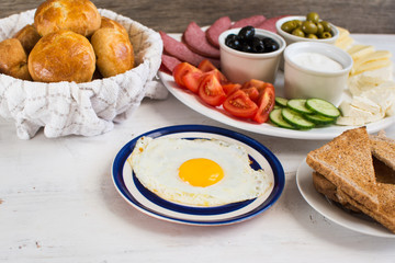 Traditional Turkish breakfast: egg, toast, pogaca pasties, vegetables, cheeses, olives and halal turkey salami, selective focus; copy space for text
