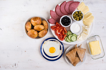 Traditional Turkish breakfast, top view: egg, toast, pogaca pasties, vegetables, cheeses, olives and halal turkey salami, selective focus; copy space for text