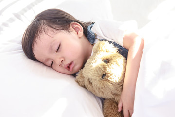 Little asian girl sleeping with her toy teddy bear