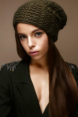 Beautiful girl in winter knit hat and khaki jacket. Young model with gentle makeup and colored...