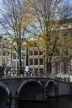 Historical brown bridge with bikes over the canal in autumn in the day in Amsterdam