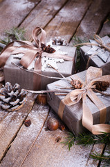 Gift boxes on old wooden background with silver stars, cones, hazelnut, anise, tape, ribbon, snowflakes.