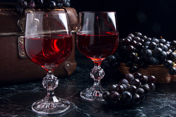 Glass of red wine on dark marble background. Cluster of blue gra