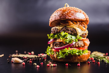 Juicy delicious burger with spices on a black background - obrazy, fototapety, plakaty