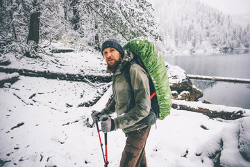 Bearded Man with backpack hiking in winter forest landscape Travel Lifestyle concept adventure...