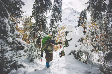 Man Traveler with backpack hiking in winter forest landscape Travel Lifestyle concept adventure...