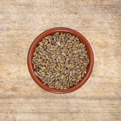 Organic milk thistle seeds in a small bowl atop an antique wood table top.