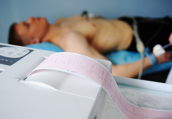 doctor with electrocardiogram equipment making cardiogram test to male patient in hospital clinic