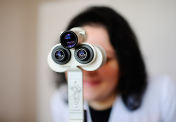Doctor woman looking into microscope closeup