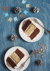 Pieces of triple chocolate cake on wooden background. Cake with white, milk and dark chocolate
