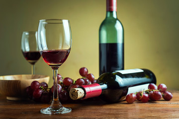Wine bottles with glass and grape on wooden table background