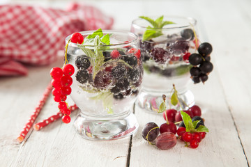 summer drink with berries and ice in a glass on a table, selective focus