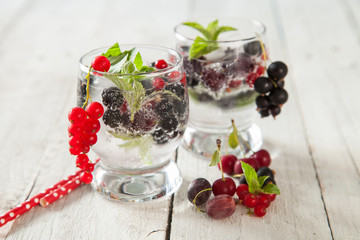 summer drink with berries and ice in a glass on a table, selective focus