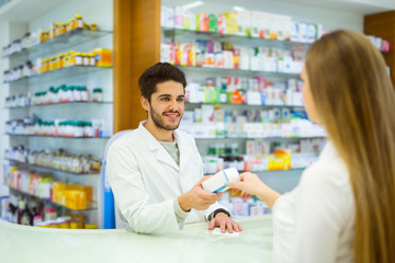 Experienced pharmacist counseling female customer in modern pharmacy