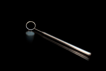 Closeup of dental mirror on black background