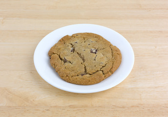 Double chocolate chip cookie on a white plate atop a wood table.