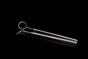 Dental mirror and dentist probe. Image isolated on black background