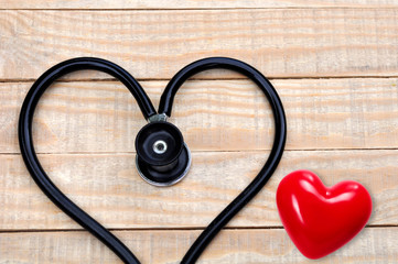 Medical stethoscope in a heart shape on wood table background