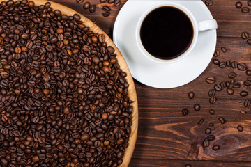 cup of coffee and coffee beans on a wooden table. Horizontal top view