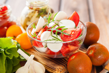 ingredients for salad - cheese, tomatoes, greens and garlic on a table, selective focus