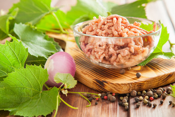 ingredients for dolma - mincemeat, onions and grape leaves on a table, selective focus
