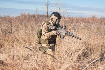 Fototapeta premium aiming, airsoft player with gun, helmet and bulletproof vest running in fields
