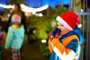 Little kid boy with hot chocolate on Christmas market