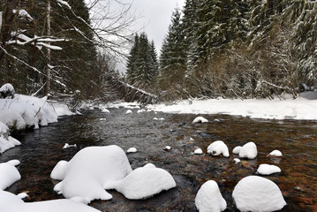 Small frozen river with fresh snow on the rocks