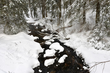 Small frozen river with fresh snow on the rocks