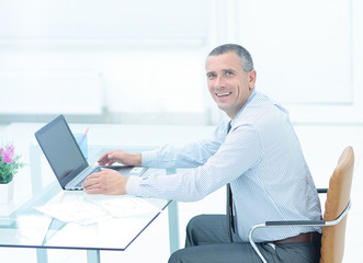 successful smiling businessman working on laptop at Desk in offi