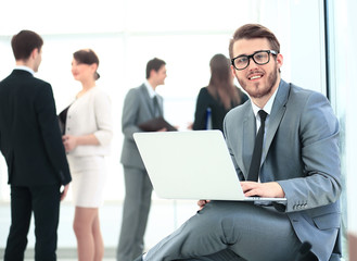 Portrait of a handsome young business man with people in background at office meeting