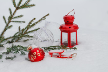 Red Christmas bauble hanging on a snowy pine branch in winter ag