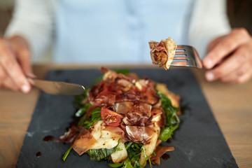 woman eating prosciutto ham salad at restaurant
