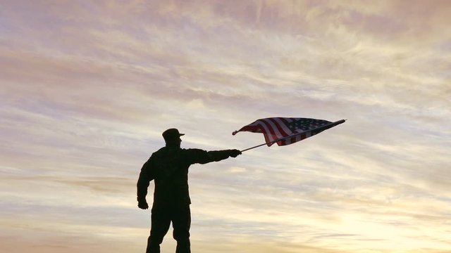 4K. Soldier silhouette waves American Flag, sunrise time  
