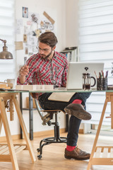 an architect,  sitting at his desk, working on his laptop