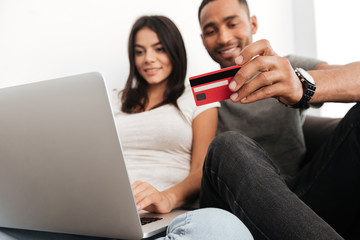 Cheerful young couple shopping online with credit card