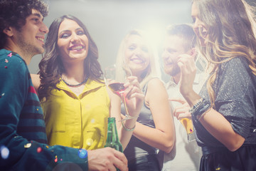 Happy friends having fun. Home party. Lot of confetti around them