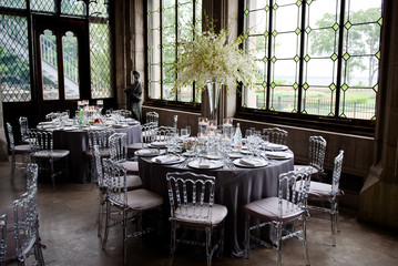 Transparent plastic chairs stand around dinner tables with dark