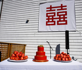 Chinese hieroglyph on white cloth hangs over red wedding cake
