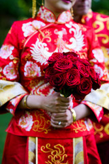 Fototapeta na wymiar Woman in Chinese national clothes holds bouquet of red roses