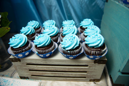 Chocolate Cupcakes With Blue Glaze And Pearls Stand On Wooden Bo