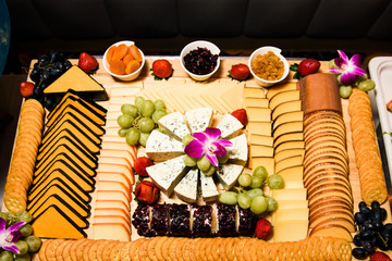 Slices of cheese lie on large plate with grape