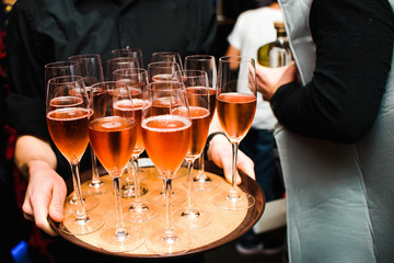 Waiter holds trey with glasses and pink champagne in them
