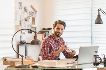 Fototapeta na wymiar an architect, sitting at his desk, working on his laptop