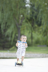 Happy Chinese baby boy playing a scooter