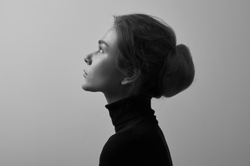 Dramatic black and white portrait of young beautiful girl with freckles in a black turtleneck on white background in studio - 129438946