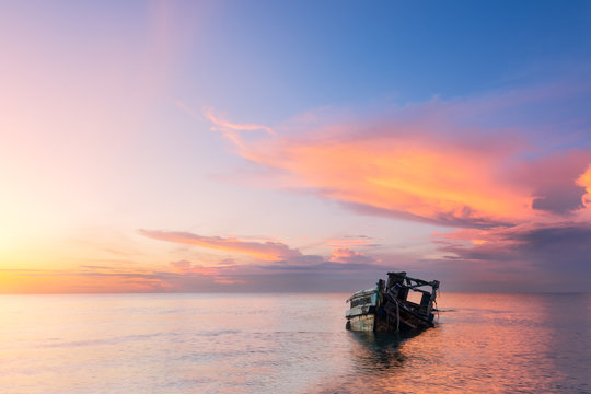 Abandoned Shipwreck Of Wood Fishing Boat On Beach At Twilight Time