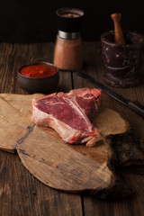Raw Steak T-Bone with spices and mortar with pepper