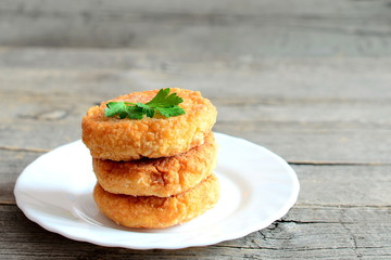 Fried pea burgers on a plate on old wooden background. Delicious homemade burgers made from yellow dried peas and decorated with fresh parsley. Vegetarian lunch or dinner idea. Closeup