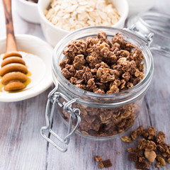 Homemade chocolate granola ingredients, nuts, oats, honey on white wooden background. Healthy breakfast concept.